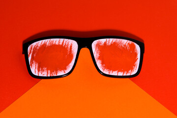 Summer concept of rest and fun. Sunglasses decorated with red paper. Isolated in orange and red. 