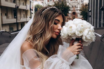 The bride is holding a bouquet of white roses. Portrait of the bride. Beautiful wedding bouquet.