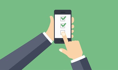 Poster - hand holding black mobile phone with check mark on the screen isolated on green.