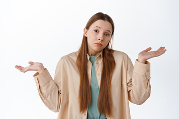 Wall Mural - Confused and clueless girl shrugging shoulders, cant tell, dont know, have no idea, standing over white background puzzled