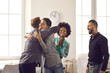 © Studio Romantic - Group of positive diverse people hugging their friend or colleague. Team of office workers embracing young man congratulating him on promotion or happy life event