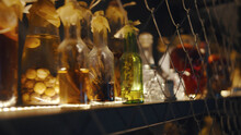 Vintage Glass Vials And Bottles On Illuminated Shelf In Cupboard With Net Fence Doors