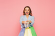 Excited shopaholic holding shopping bags isolated on pink