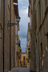 Sticker - Beautiful view of a narrow street with buildings leading to a yellow building on a gloomy day