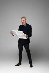 Wall Mural - full length of middle aged man in glasses and suit reading economic news on grey