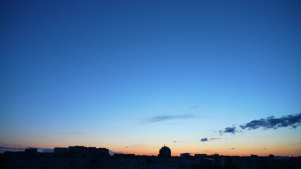 Wall Mural - sunset time and clear blue sky with some white fluffy clouds over dark night cityscape