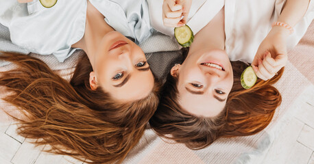 Wall Mural - two girls make homemade face and hair beauty masks. cucumbers for the freshness of the skin around t