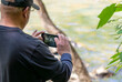 A middle age white man takes a picture of a river with his smart phone.