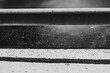 A black and white photo of a messy spiderweb woven between a metal rail and a concrete wall. Focus is on the center of the spider web