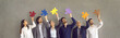 Team of happy business people standing in row holding colorful jigsaw pieces. Group of smiling entrepreneurs, colleagues, office coworkers looking at different puzzle parts. Banner, teamwork concept