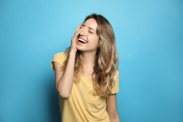 Sticker - Cheerful young woman laughing on light blue background