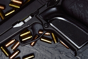 Top view of gun and ammunition. Close-up of pistol and bullets. Firearms on black concrete table. Weapon of crime or defense.