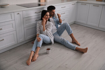 Poster - Happy couple sitting on warm floor in kitchen. Heating system