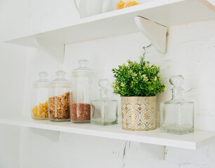 Wall Mural - Kitchen interior. A shelf with a vase of flowers and glass jars of cereals and pasta.