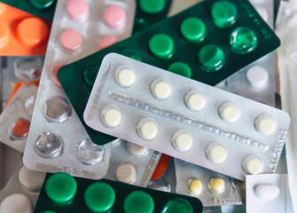 bunch of medical pills in white, pink, green and other colors. Tablets in plastic packaging. Health care and medicine concept. Pharmaceutical industry concept.