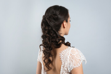 Wall Mural - Young bride with beautiful wedding hairstyle on light grey background