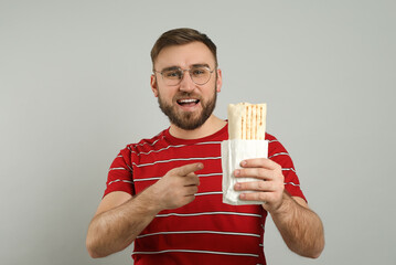 Wall Mural - Young man with delicious shawarma on grey background