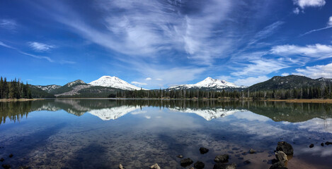 Wall Mural - two volcanic mountains rise out of the distant forrest. a tranquil lake in the foreground reflects t