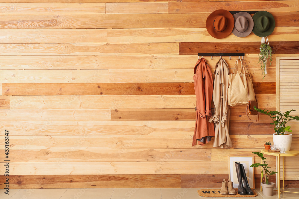 Hangers with clothes and hats on wooden wall - obrazy, fototapety, plakaty 