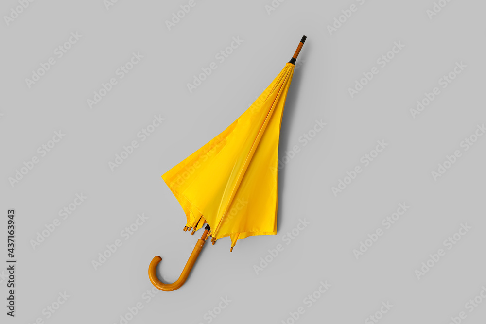 Stylish yellow umbrella on light background