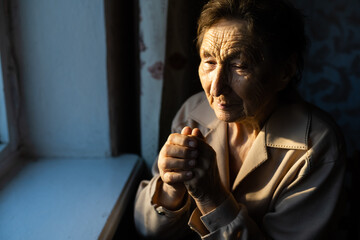 Very old woman is praying in her country style kitchen