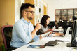 © JustLife - Colleagues in office. Businesswoman and businessman discussing work in office. Two friends working together.