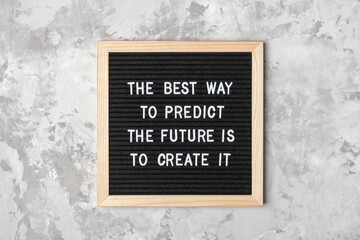 Wall Mural - The best way to predict the future is to create it. Motivational quote on black letter board on gray background. Concept inspirational quote of the day. Greeting card, postcard