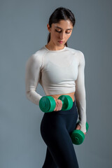 Wall Mural - Sporty girl performing arm exercises with dumbbells on grey background