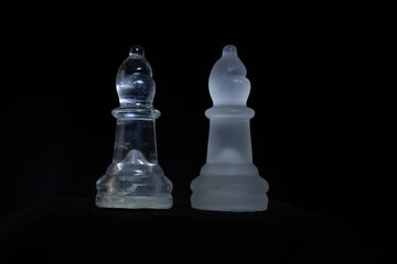 two white bishop chess pieces isolate on a black background with white light