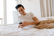 © Drobot Dean - Smiling young hispanic man using mobile phone