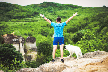 Wall Mural - man with his dog sitting on a rock enjoying nature