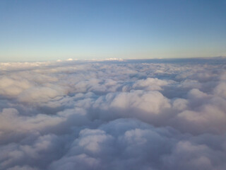 Aerial high flight above the clouds at sunrise.