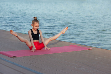 beautiful young slim girl doing yoga or gymnastic exercise by the lake. healthy lifestyle. children'