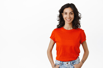image of young caucasian woman with curly dark hair, stands in red t-shirt with happy relaxed smile,