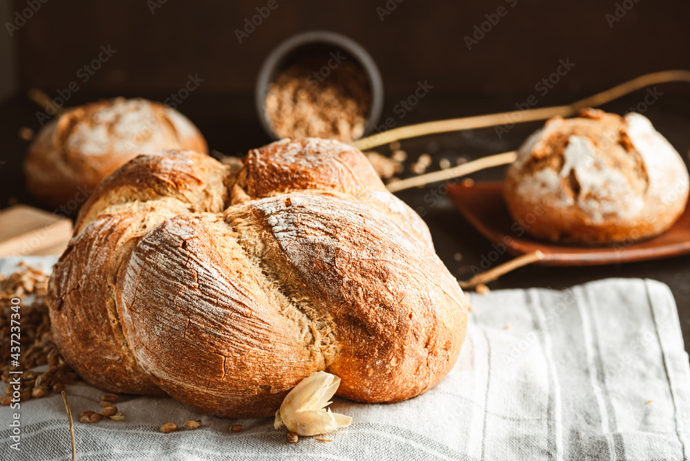 Bread on dark background. Fresh crispy baking, old style. - obrazy, fototapety, plakaty 