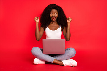 Sticker - Full body photo of young attractive afro girl happy positive smile look laptop rejoice victory isolated over red color background