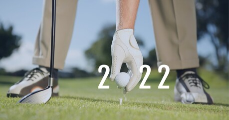 Composition of 2022 number with golf ball placed by golf player on tee on golf course