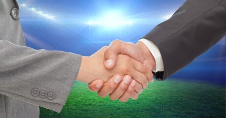 Composition of business people shaking hands over sports stadium