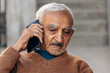 © Yashvi - Close up shot of sad Indian senior man sits in the house in a lonely and sad mood talking on the phone. Lonely old age.