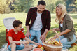 © gstockstudio - Happy young mother and father with little boy smiling while having picnic outdoors