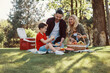 © gstockstudio - Happy young mother and father with little boy smiling while having picnic outdoors