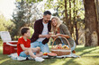 © gstockstudio - Happy young mother and father with little boy smiling while having picnic outdoors