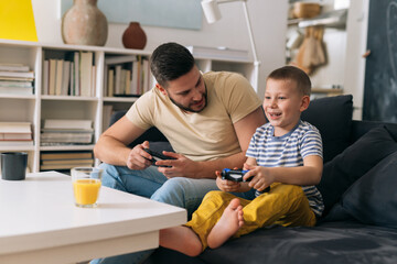 Wall Mural - father and son playing video games with controllers at home