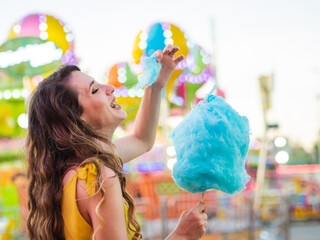 Wall Mural - Attractive Caucasian female posing with blue cotton candy at a carnival