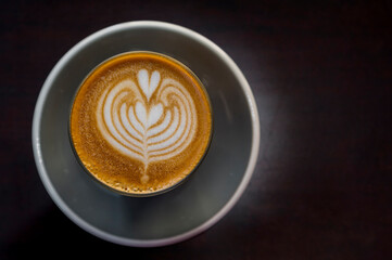 cup of hot latte art coffee on wood table in morning sun light, relax time