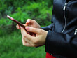 the girls are holding the phone in their hands. Side view shot of woman's hands using smart phone in nature, online shopping concept.