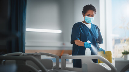 Hospital Ward: Professional Black Nurse Wearing Face Mask, Wiping the Bed, Cleaning Room After Covid-19 Patients Recover. Disinfection, Sterilizing, Sanitizing Clinic after Coronavirus Infected People