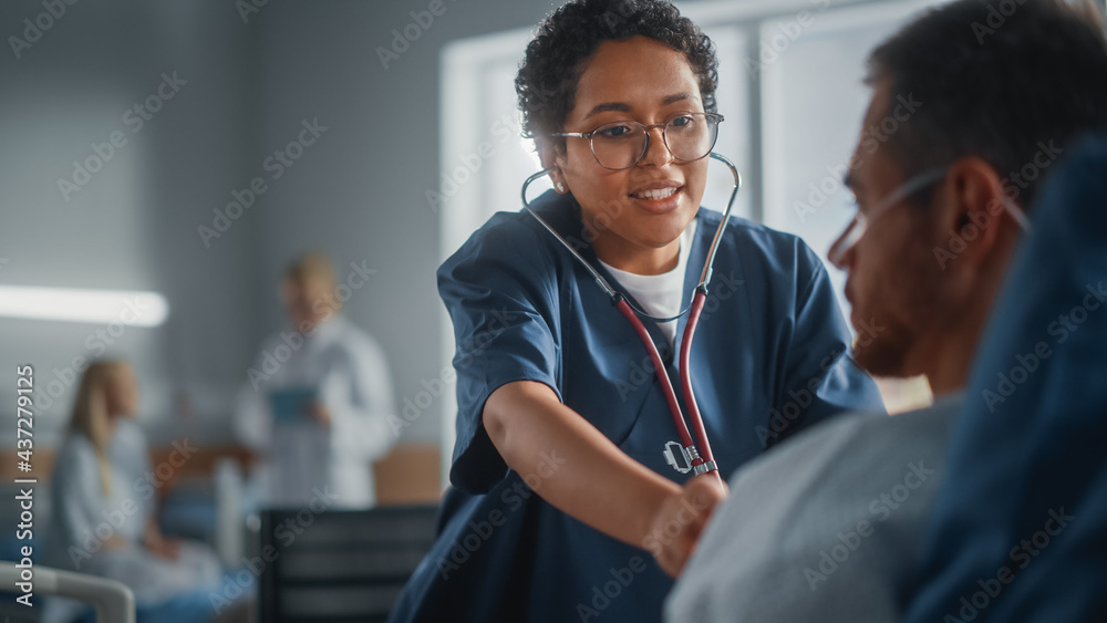 Hospital Ward: Friendly Black Head Nurse Uses Stethoscope to Listen to Heartbeat and Lungs of Recovering Male Patient Resting in Bed, Does Checkup. Man Getting well after Successful Surgery - obrazy, fototapety, plakaty 