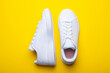 Pair of casual shoes on yellow background. Top view of stylish sneakers on color background