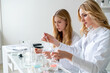 © Вадим Каштанов - Team of two attractive medical chemistry laboratory assistants passionate about their work. Pour liquid into flat-bottomed flask with pipette. Vaccine Creation. Pandemic covid-19.